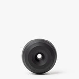 The HMM Paperweight Pen Stand (Black) is a circular aluminum piece with concentric raised rings and a central hole, shown on a plain white background.