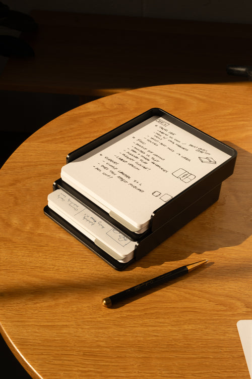 The Analog Capture Kit - 2 Large (Black Aluminum) features dot grid cards in a sleek black aluminum tray, with a pen nearby on a wooden table—everything you need to capture your ideas in style.