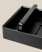 An Analog Archive (Black Aluminum) desk organizer made of solid black aluminum with a central divider featuring a white U-shaped logo.
