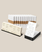 The Analog Annual Kit (Black Aluminum) includes stacked white notepads with brown bands, a Weekly Card Holder for your to-do list, and a black tray with a calendar layout—ideal for organizing your year.