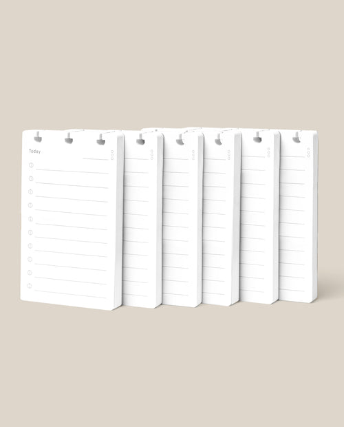 Six white Discbound Analog Refill notepads (6-pack) with blank lines and checkboxes are arranged side by side on a beige background. Each notepad features a top cutout, ideal for hanging, binding, or use as discbound refill cards.