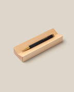 The Pen & Pen Tray Bundle (Black/Maple) features a sleek black and gold pen resting on a light maple tray against a plain beige background.