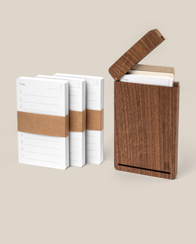 The Analog Travel Case + 3 Card Packs (Walnut) features three stacks of white task cards with brown bands beside an open premium walnut case holding matching notecards, all displayed on a beige background.
