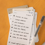 A close-up of a handwritten to-do list on premium Analog Trial Pack card stock, featuring photo shoot tasks and a pen, with other 3x5 cards partially visible underneath on an orange surface. The date 4.13.25 is at the top.