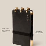 The Leather Discbound Analog (Black) is made from full-grain black leather, features three gold discs at the top, an elastic pen loop with a black and gold Ugmonk pen (sold separately), supports Analog Task Cards, and has four silver rivets on the right.