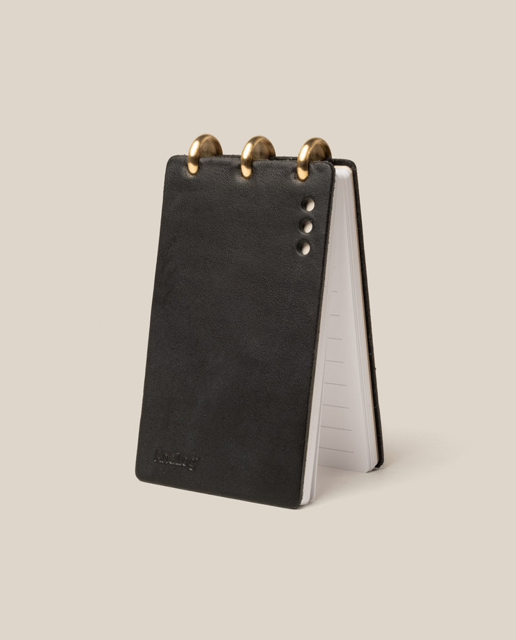 Black leather notepad with gold accents on a beige background