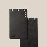 Two black leather card holders on a beige background