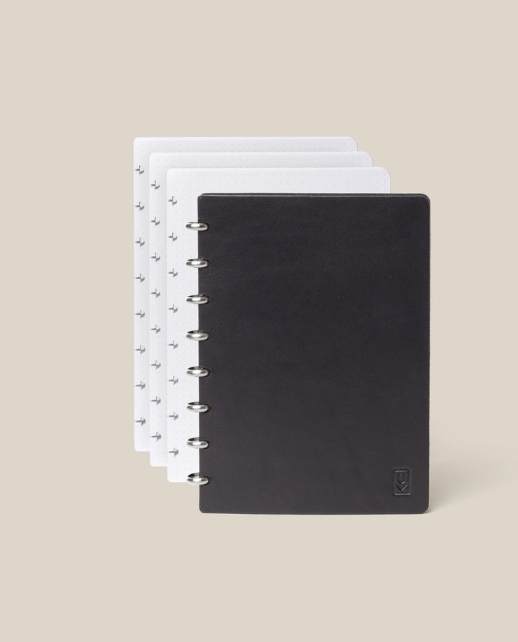 The Discbound Heirloom Journal Bundle in black leather (Standard 6" x 8.5" with 3 refills) is displayed fanned open to show four dotted pages, against a plain beige background.