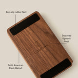 The Analog Daily Focus Kit (Walnut) is a rectangular solid American black walnut card holder with an engraved Ugmonk logo at the center and two black non-slip rubber feet on opposite underside edges.