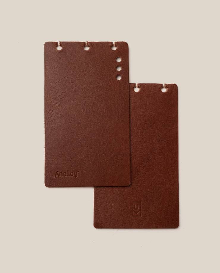 Two brown leather notebooks on a beige background