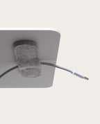 A close-up of the Warehouse Item - Magnetic Cable Keepers (Set of 2 - Light Gray), one of the most practical solutions for organizing cables, attached to the corner of a white surface and holding a white USB-C cable—an essential addition to your collection of monitor stand accessories.