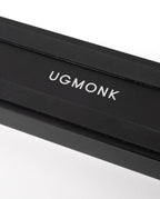 A sleek black rectangular box with "UGMONK" in white capitals on the lid, ideal for storing the Analog Card Bar (Small 10" - Black), photographed against a white background.