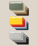Eighteen Analog Card Sleeve Multipack - Small holders are displayed in an array of colors such as green, tan, brown, yellow, red, blue, gray, and black—each acting as a stylish card organizer that securely holds a white card against a beige background.