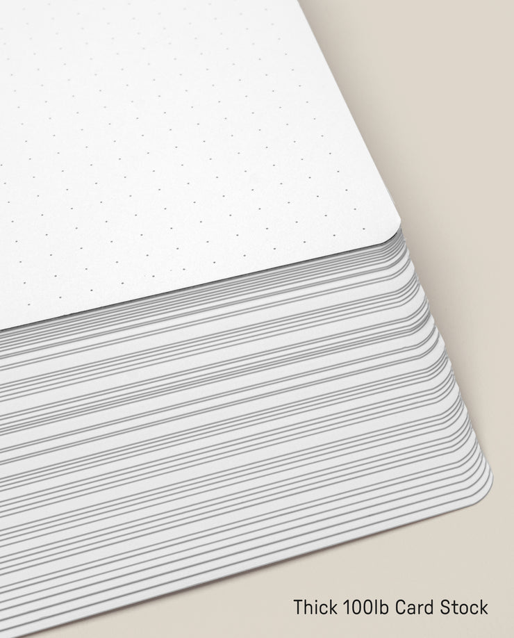 A stack of Analog Dot Grid Cards - Large (1-Pack) features thick, white, rounded-corner cards with a subtle dotted pattern and "Thick 100lb Premium Card Stock" labeled in the bottom right corner on a beige background.