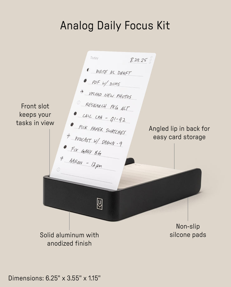 The Analog Daily Focus Kit + 6 Refills (Black Aluminum) is a rectangular black aluminum desk tray with a front card slot, angled lip, non-slip silicone pads, solid build, and measures 6.25 x 3.55 x 1.15 inches.