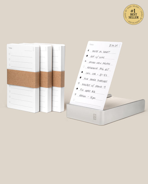 Four stacks of Analog Daily Focus Kit + 3 Refills (Silver Aluminum) task cards are shown; one stack sits in a sleek silver aluminum holder displaying a handwritten to-do list. A #1 Best Seller badge appears in the top right corner.