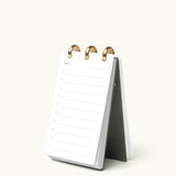 The Discbound Analog + 3 Refills is a stylish, refillable standing flip notepad with brass disc binding, shown open to a blank daily planner page with numbered lines—a perfect workspace task planner.