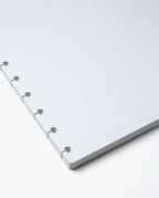 A close-up of the Discbound Journal Refill (Large 8.5" x 11" - 3 Pack), featuring white dot grid paper with multiple round punch holes along the left edge, designed for discbound notebooks, shown against a plain white background.