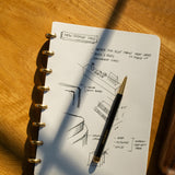 The Discbound Journal (Standard 6"x 8.5") is a refillable notebook with a pen, featuring solid brass discs for a sleek and durable discbound design.