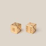 Two gold dice with U monogram on a beige background