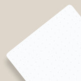 A pack of Analog Dot Grid Cards - Small (3-Pack) rests at an angle on a light beige surface, featuring subtle gray dots for easy note taking and casting a soft shadow to the left.