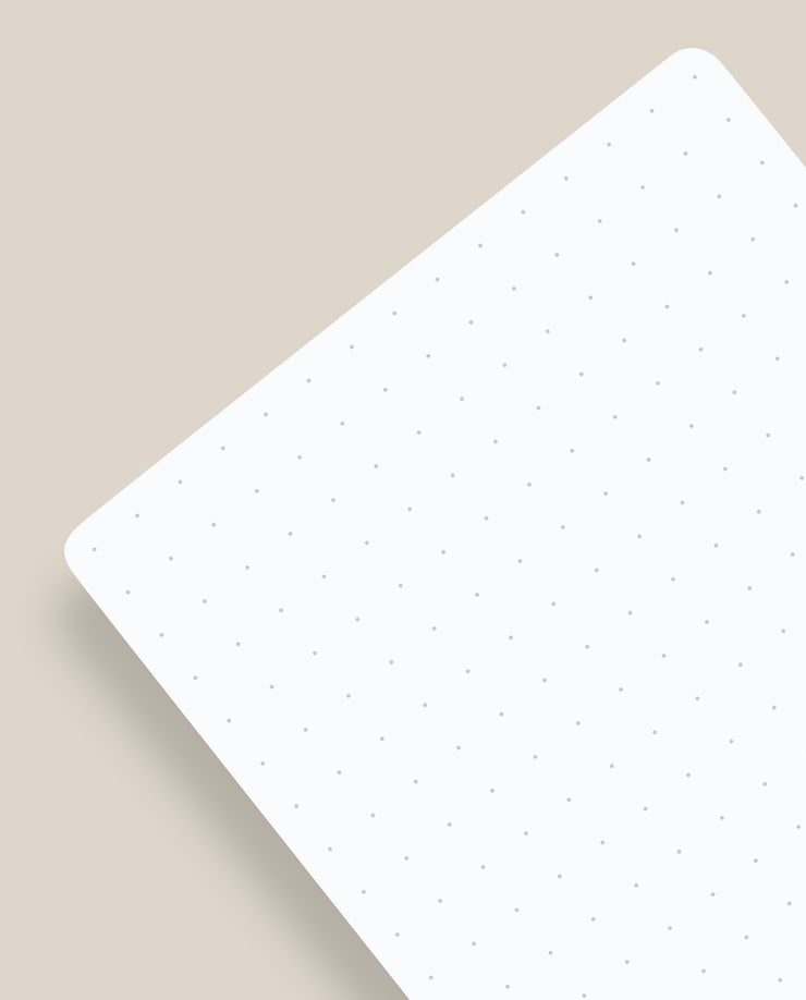 A close-up of an Analog Dot Grid Card - Small (1-Pack) shows its white, rounded-corner sheet with evenly spaced grey dots, resembling a tiny grid, resting on a beige surface and casting a soft shadow.