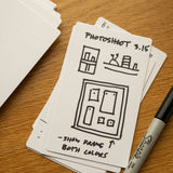 A stack of Analog Dot Grid Cards - Small (3-Pack) sits on a wooden surface, the top card filled with sketches and notes for Photoshoot 3.15: "show frame both colors." A black Sharpie rests nearby, ready for more ideas.