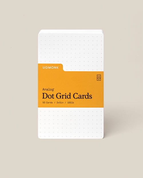 A stack of Analog Dot Grid Cards - Small with a white cover, orange label, and dotted grid. Includes 50 cards (3x5in) made from 100lb uncoated cardstock—perfect for sketching ideas.
