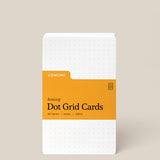 A stack of Analog Dot Grid Cards - Small with a white cover, orange label, and dotted grid. Includes 50 cards (3x5in) made from 100lb uncoated cardstock—perfect for sketching ideas.