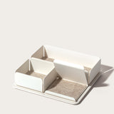 The Gather 2x2 Organizer Set (White) is a rectangular, minimalist desk organizer with three varied compartments on a flat powder-coated steel base. Each compartment is lined with light beige felt and placed against a plain, light background.