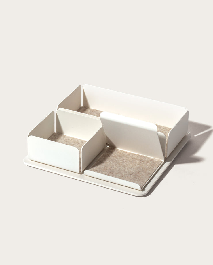 The Gather 2x2 Organizer Set (White) is a rectangular, minimalist desk organizer with three varied compartments on a flat powder-coated steel base. Each compartment is lined with light beige felt and placed against a plain, light background.