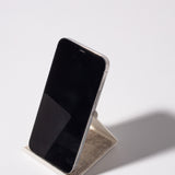 A smartphone with a black screen stands upright on the white, powder-coated Gather 2x2 Organizer Set, casting a shadow on a plain white surface—perfect for complementing your customizable desk setup.