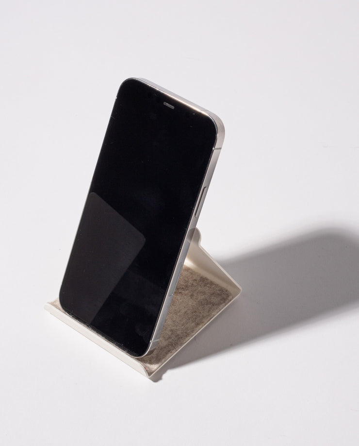 A smartphone with a black screen stands upright on the white, powder-coated Gather 2x2 Organizer Set, casting a shadow on a plain white surface—perfect for complementing your customizable desk setup.
