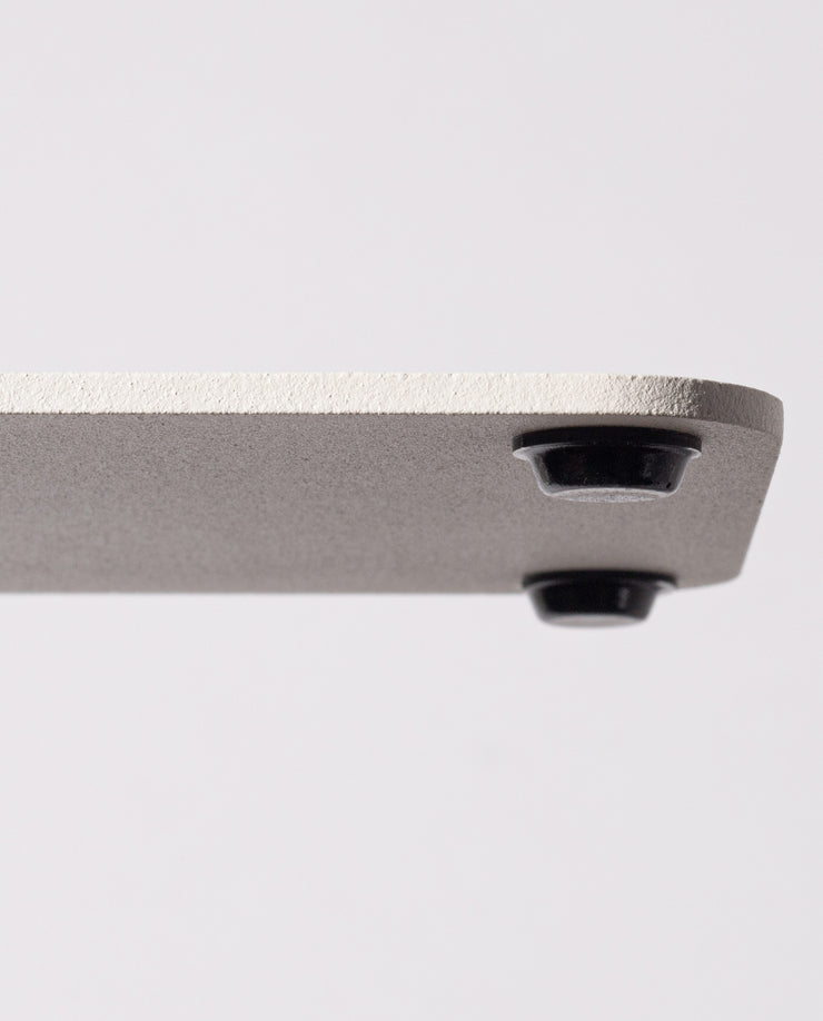 Close-up of the corner of a Gather 2x2 Organizer Set (White), showing its powder-coated steel with a textured finish and a round black foot on the underside, set against a plain light background.