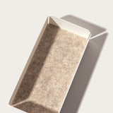 The Gather 2x2 Organizer Set (White) features a rectangular, customizable desk organizer with white powder-coated steel sides and a textured light brown base, shown on a light surface casting a sharp shadow to the right.
