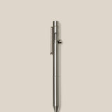 An INVENTERY Bolt Action Pen (Stainless) with a sleek clip is centered vertically on a plain light beige background.