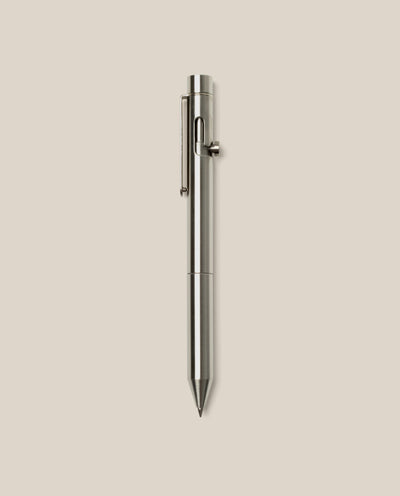 An INVENTERY Bolt Action Pen (Stainless) with a sleek clip is centered vertically on a plain light beige background.