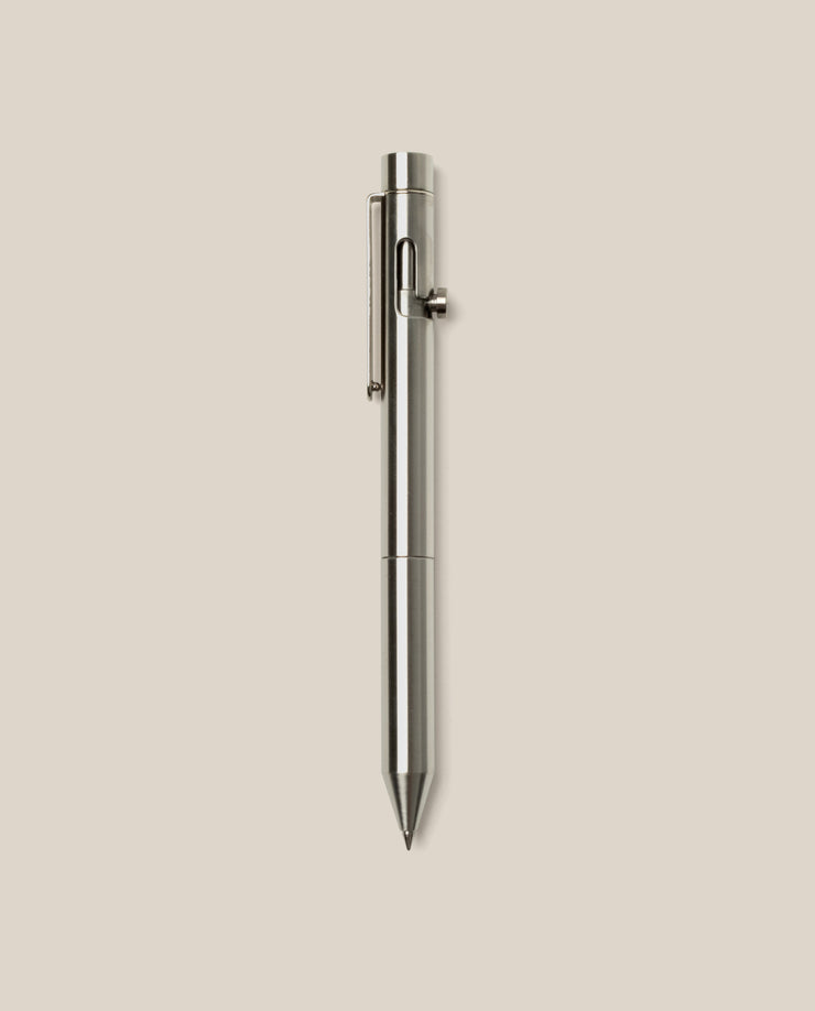 An INVENTERY Bolt Action Pen (Stainless) with a sleek clip is centered vertically on a plain light beige background.