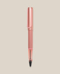 The LAMY AL-star Rollerball (Flamingo) features a pink anodized aluminum body, clear grip, and black ink tip, shown vertically on a light beige background for smooth writing.