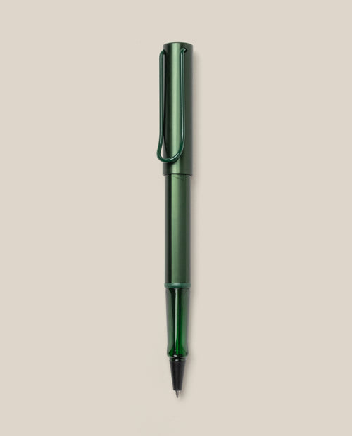 A LAMY AL-star Rollerball (Pine) pen in green metallic, with matching cap and clip, is displayed vertically on a plain light beige background. This refillable pen ensures smooth, effortless writing.
