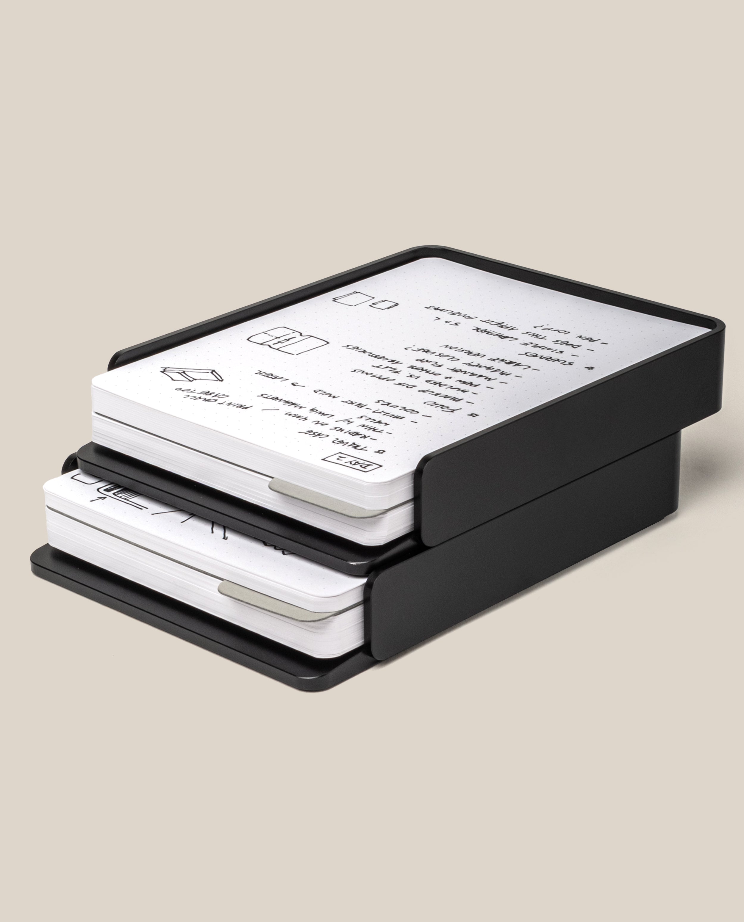 The Analog Capture Kit - 2 Large (Black Aluminum) is a two-tier desk organizer tray holding stacks of paper and dot grid cards with handwritten notes and diagrams, displayed on a light beige background.