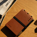 Brown notebook with a pen on a wooden surface