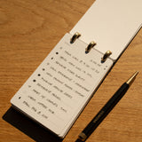 Notebook with handwritten to-do list on a wooden surface with a pen next to it
