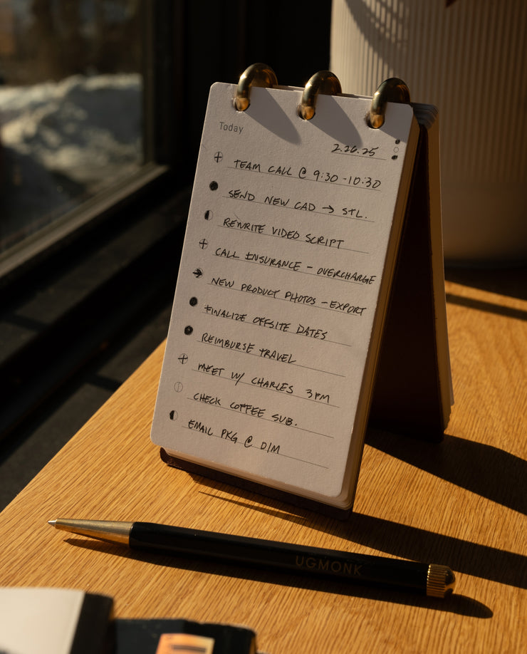 Flip chart with a to-do list on a wooden surface with a pen next to it