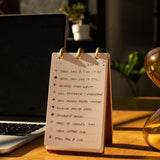 Notebook with a to-do list on a desk next to a laptop