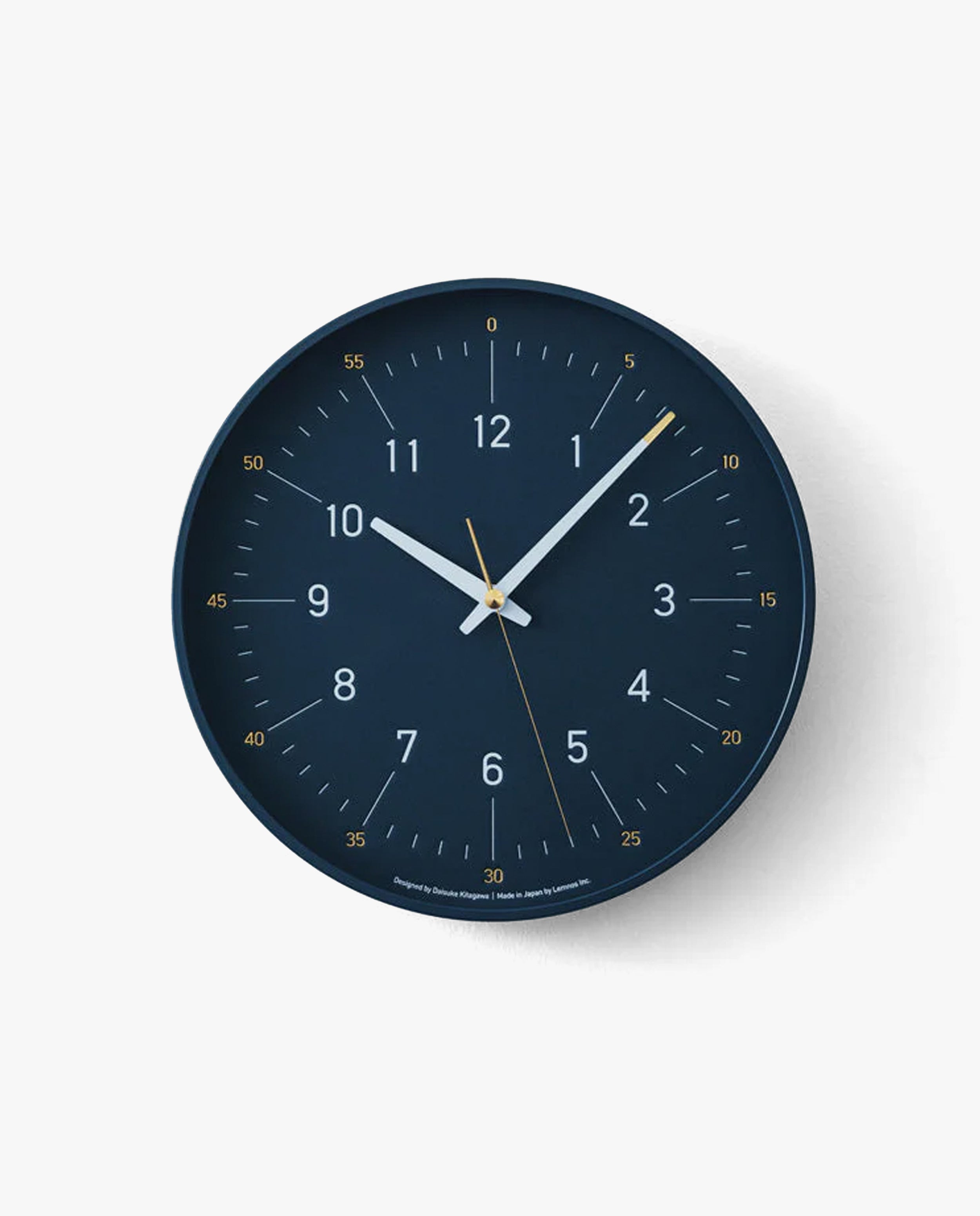 The Lemnos Essent Wall Clock (Navy) features a dark blue designer face with striking white and yellow hands displaying the time as 5:00:27, accented by yellow minute markers on a minimalist white background—an ideal embodiment of modern design that could easily stand alongside iF Design Award winners.