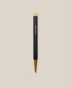 A Ugmonk Pen (Leuchtturm1917 Drehgriffel - Black) with gold accents and UGMONK in gold lettering on the barrel, shown against a plain beige background.