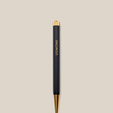 A Ugmonk Pen (Leuchtturm1917 Drehgriffel - Black) with gold accents and UGMONK in gold lettering on the barrel, shown against a plain beige background.