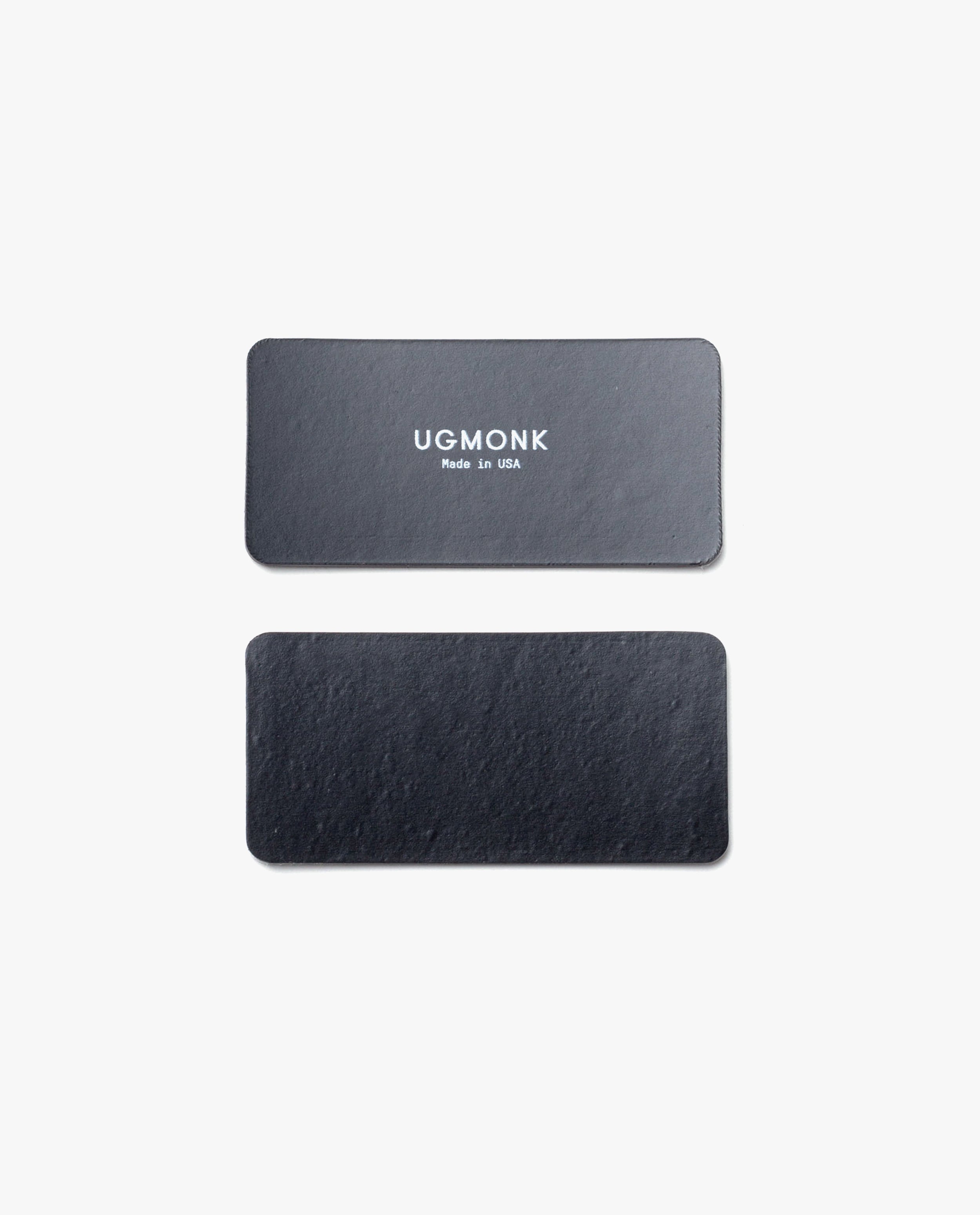 Two rectangular black leather labels are shown on a plain white background. The top label, intended for the Warehouse Item - Magnet Kit (For Analog Card Holder), features "UGMONK Made in USA" printed in white; the bottom label is blank.