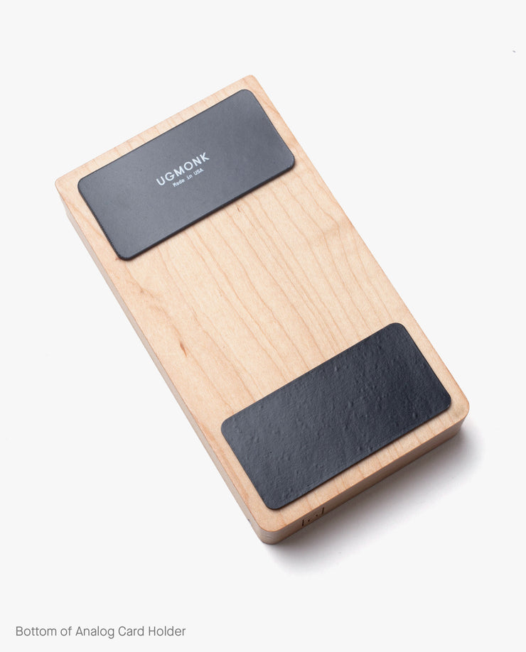 The Magnet Kit (For Analog Card Holder) includes two black rectangular pads, one with the UGMONK logo. These strong adhesive magnets ensure secure placement and are shown on a white background.